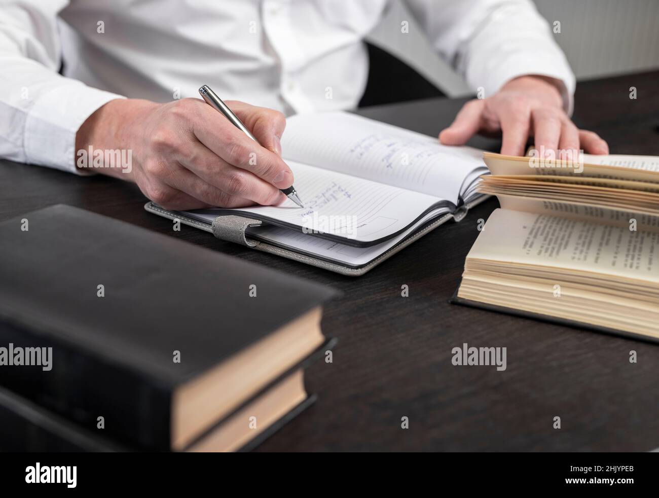Homme mains prendre des notes dans le planificateur.Homme d'affaires assis à table avec des livres ou des codes à la maison ou au bureau et écrivant une thèse ou des pensées.Concept d'apprentissage et d'éducation aux entreprises.Photo de haute qualité Banque D'Images
