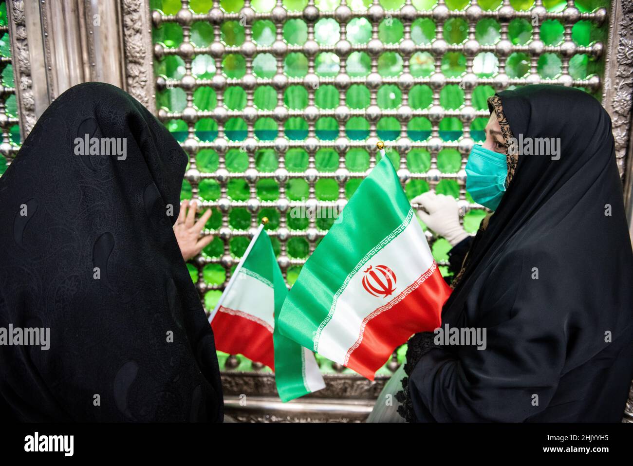 Téhéran, Téhéran, Iran.1st févr. 2022.Une femme voilée portant un masque  facial protecteur porte un drapeau iranien alors qu'elle prie en se tenant  près de la tombe de l'ayatollah Ruhollah Khomeini, ancien dirigeant