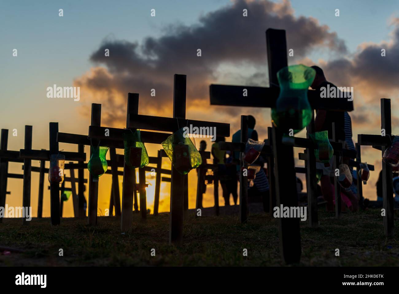 Silhouette de personnes et de croix fixées sur le sol en l'honneur de ceux tués par le Covid-19.Coucher de soleil à Salvador, Bahia, Brésil. Banque D'Images