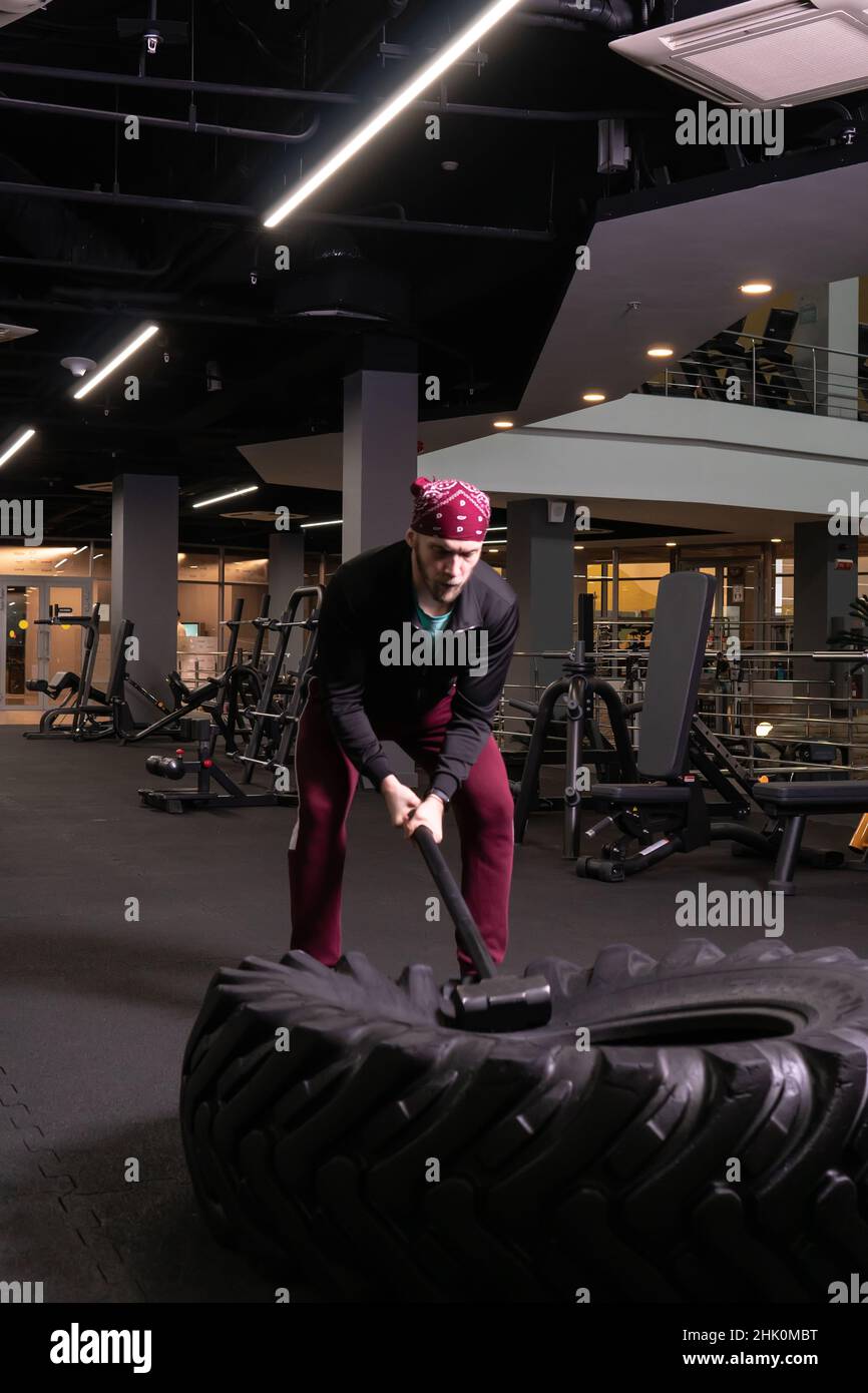 Un homme frappe une roue de sledgehammer en forme physique, le concept d'un style de vie sain masculin sledgehammer sport physique actif, de l'équipement de force pour TI Banque D'Images