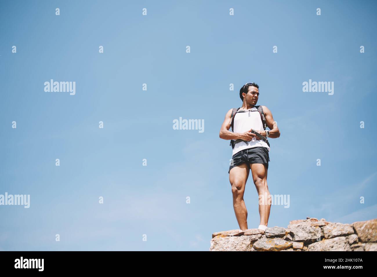 Jeune homme actif avec sac à dos debout sur la falaise Banque D'Images