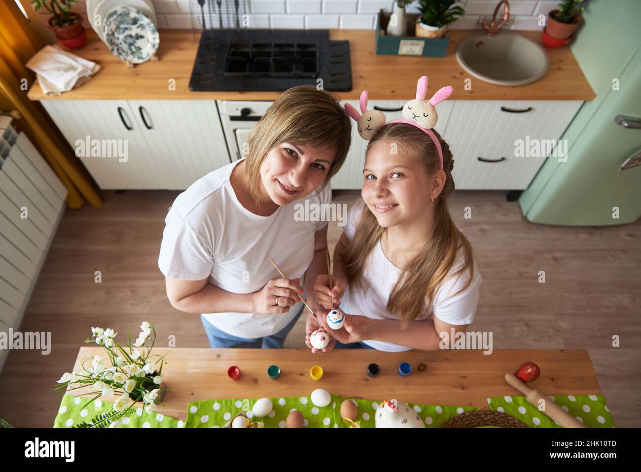 Portrait de mère et de fille se préparent pour Pâques et peindre des oeufs avec des pinceaux, vue de dessus. Banque D'Images