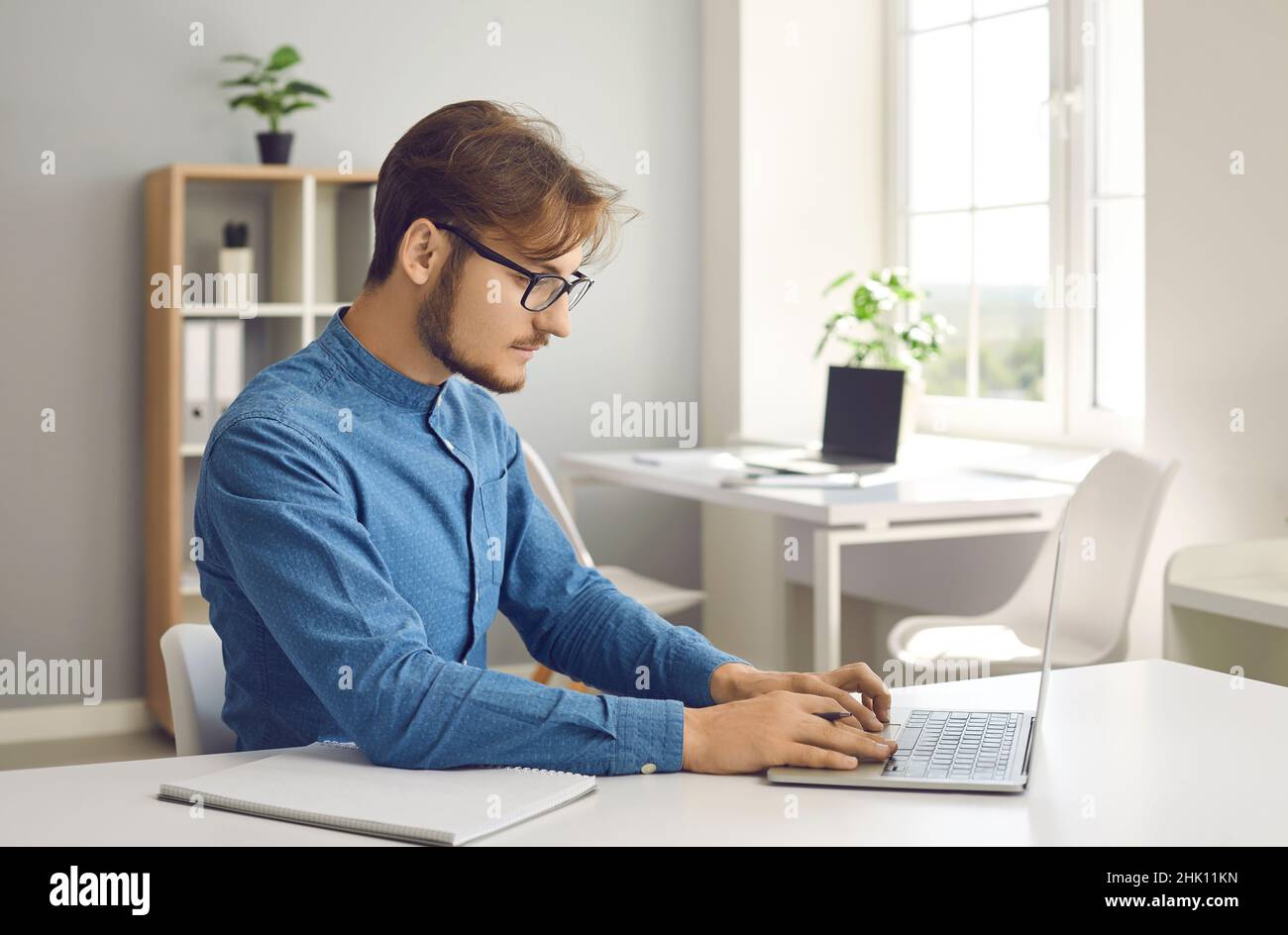 Portrait d'un jeune homme sérieux travaillant dur sur un ordinateur portable dans un centre de travail moderne et lumineux. Banque D'Images