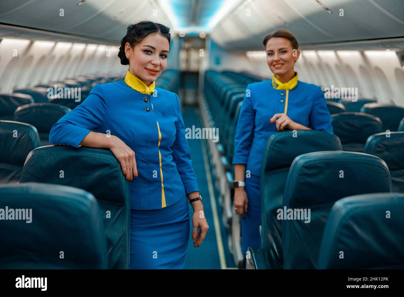 Hôtesses gaies debout dans le salon de passagers d'avion Banque D'Images