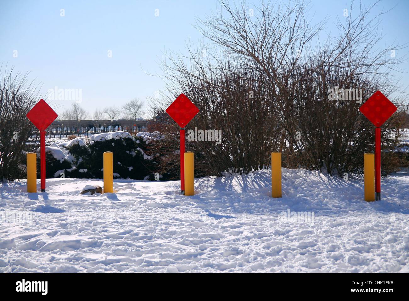 Signe carré rouge de la route avec trois poteaux jaunes sur la neige dans une journée ensoleillée après une tempête Banque D'Images