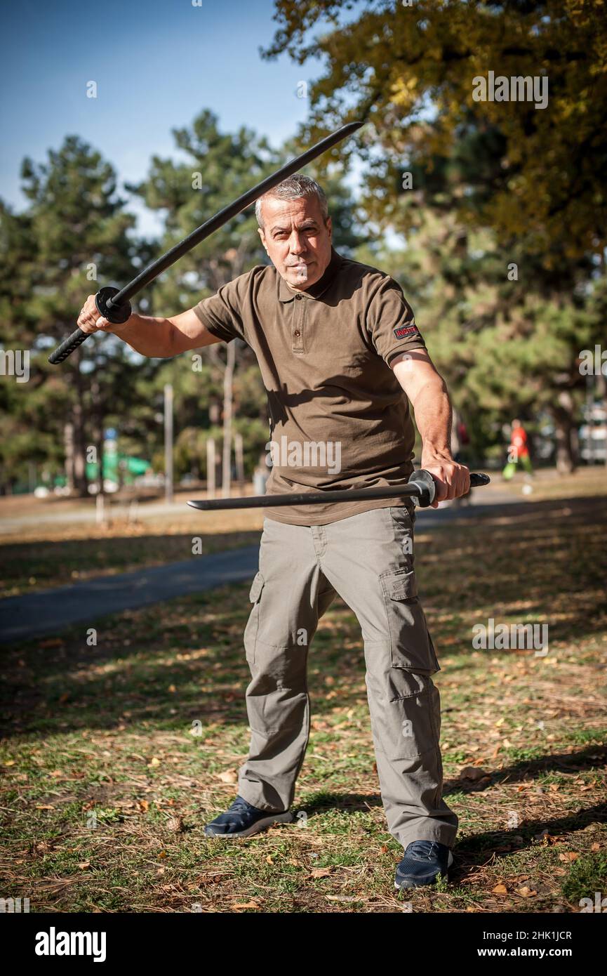 L'instructeur démontre les techniques de lutte contre l'épée de katana et les méthodes d'entraînement dans le parc public.Démonstration avec arme en plastique.Arme à long couteau tra Banque D'Images