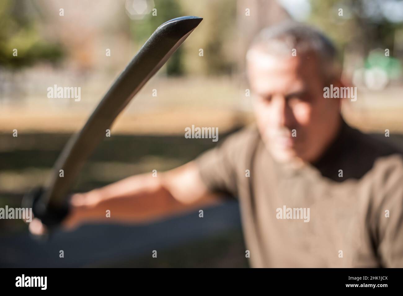 L'instructeur démontre les techniques de lutte contre l'épée de katana et les méthodes d'entraînement dans le parc public.Démonstration avec arme en plastique.Arme à long couteau tra Banque D'Images