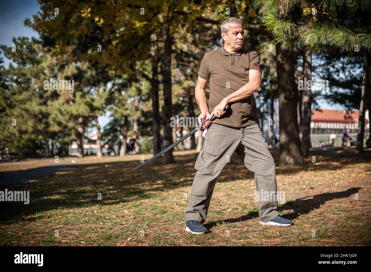 L'instructeur démontre les techniques de lutte contre l'épée de katana et les méthodes d'entraînement dans le parc public.Démonstration avec arme en plastique.Arme à long couteau tra Banque D'Images