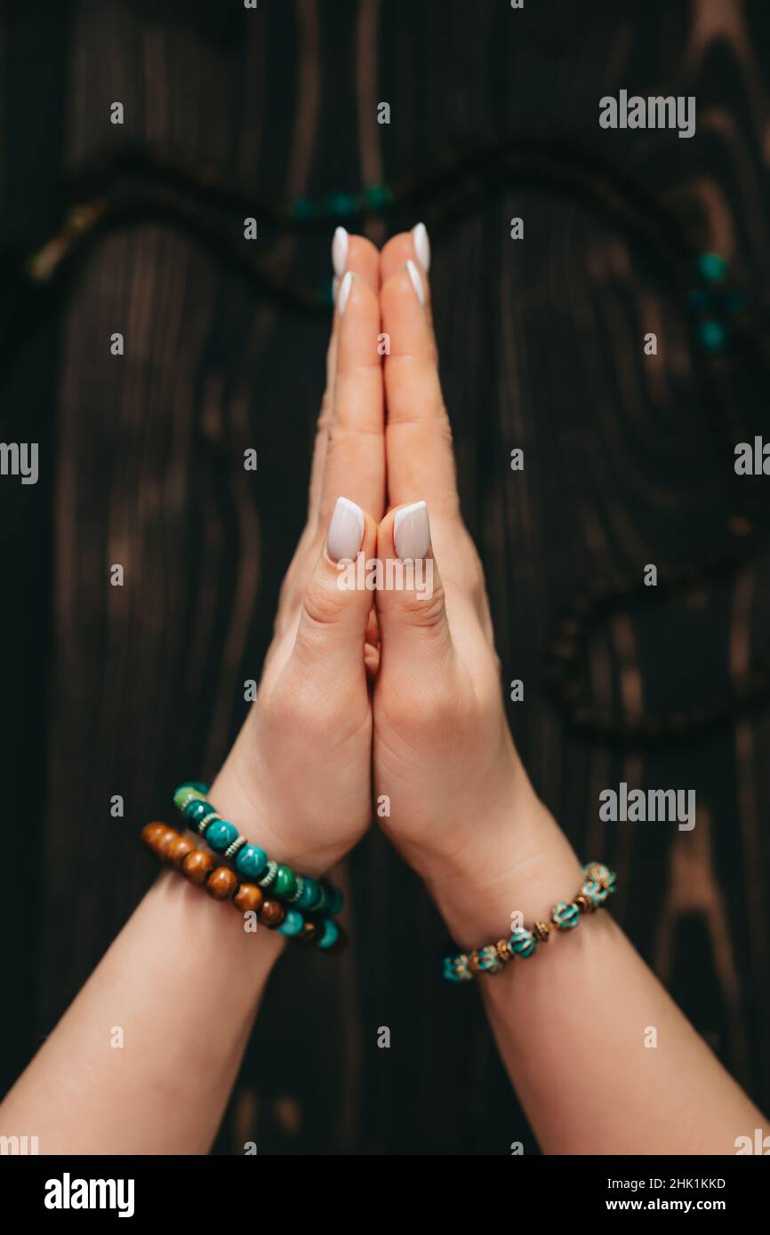 Femme lisant des mantras ou des prières, mains pliées en namaste devant le rosaire ou perles de mala sur fond en bois.Spiritualité, religion, Dieu Banque D'Images
