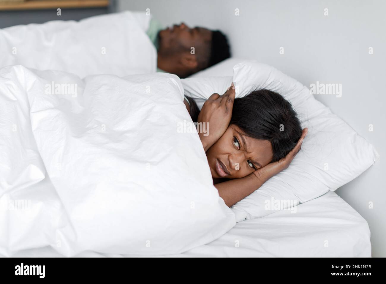 Une jeune femme afro-américaine triste et déprimée se réveille du ronflement et du bruit de son mari endormi Banque D'Images