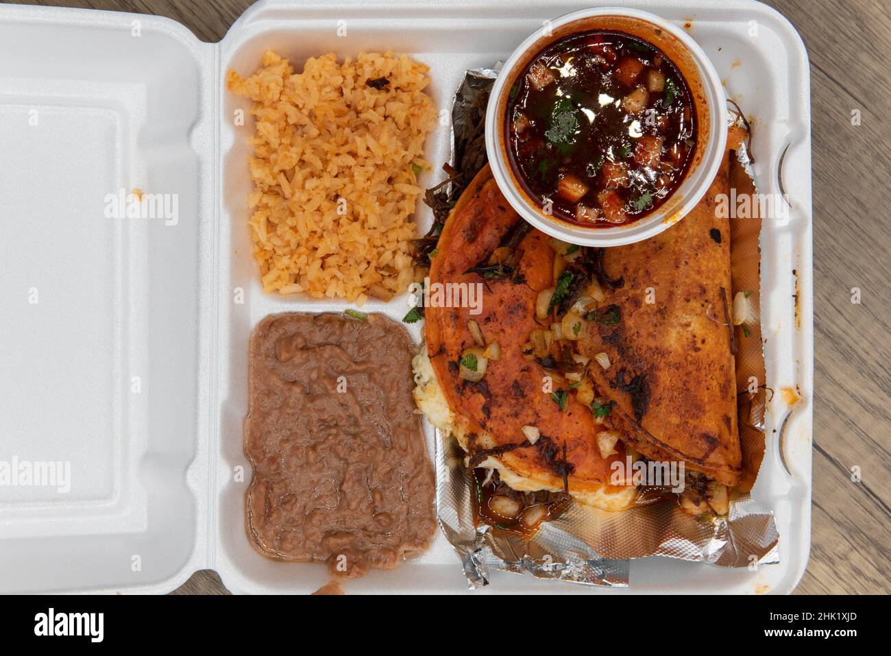 Vue en hauteur de l'ordre de prendre des tacos birria frits à la perfection avec du riz et des haricots dans la boîte en mousse de polystyrène. Banque D'Images