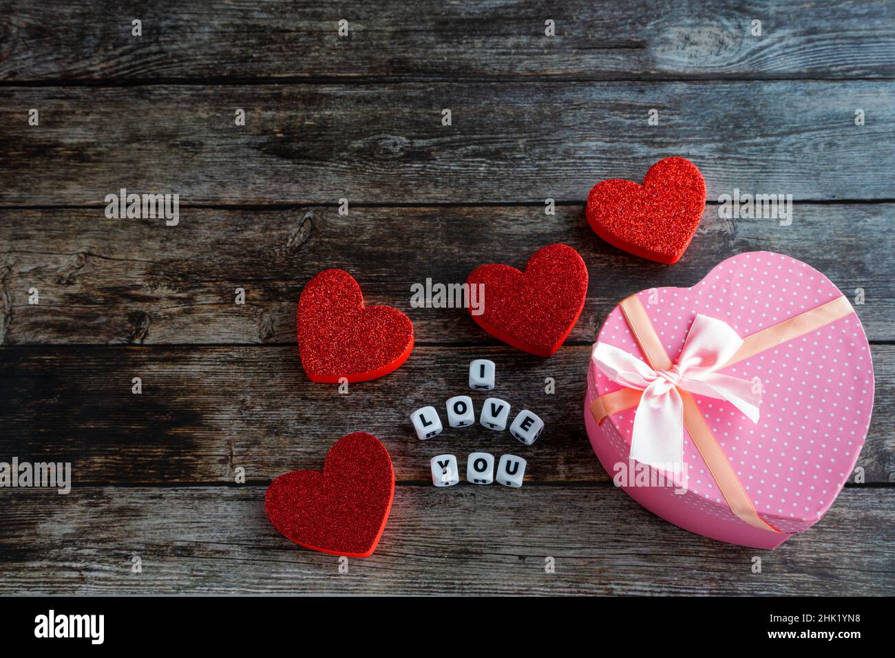 Boîte cadeau de Saint-Valentin en forme de coeur rose sur table en bois avec texte et espace de copie I Love You. Banque D'Images