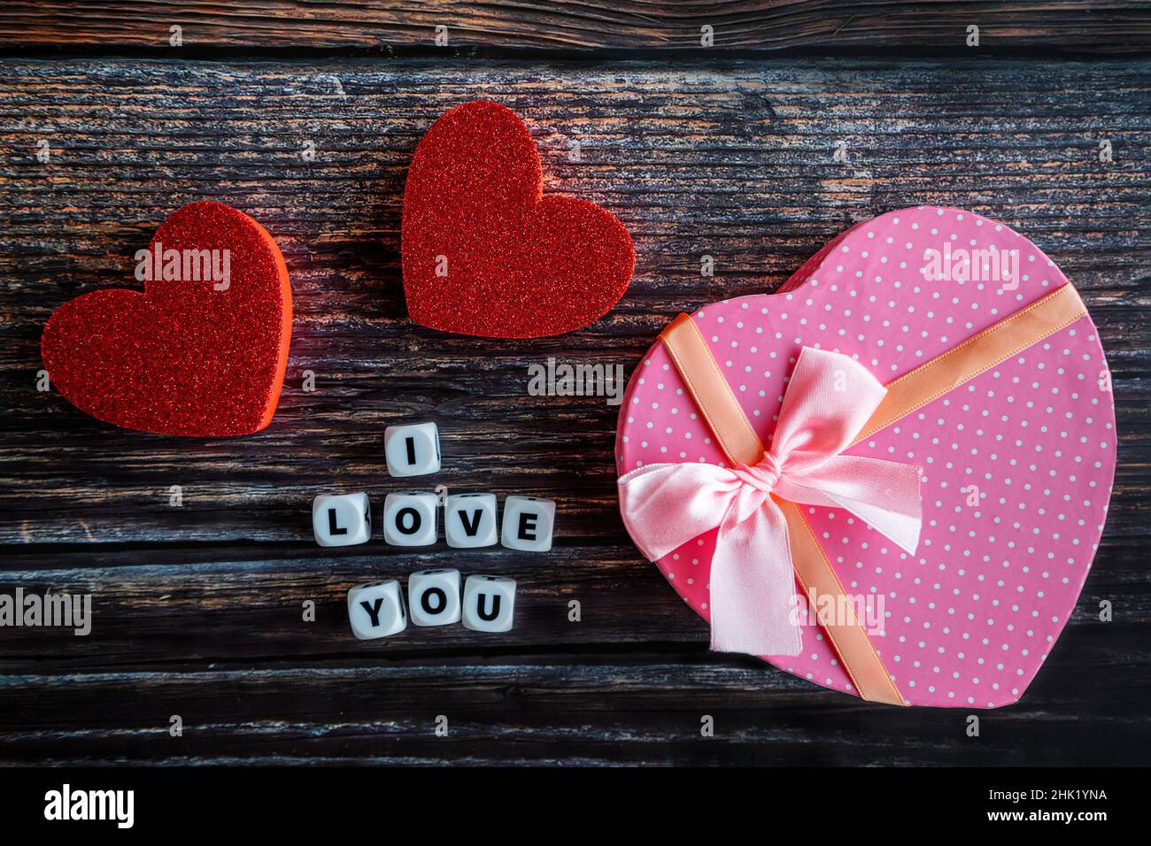 Boîte cadeau de Saint-Valentin en forme de coeur rose sur table en bois avec texte et espace de copie I Love You. Banque D'Images
