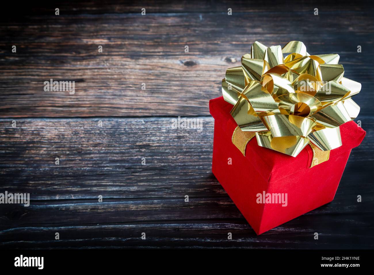 Boîte cadeau rouge sur table rustique en bois avec espace pour les copies, idéale pour Noël, la Saint-Valentin, les occasions spéciales Banque D'Images