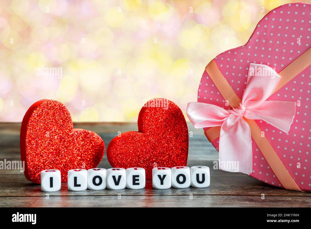 Boîte cadeau de Saint-Valentin en forme de coeur rose sur une table en bois avec deux coeurs et je vous aime message, copier l'espace. Banque D'Images
