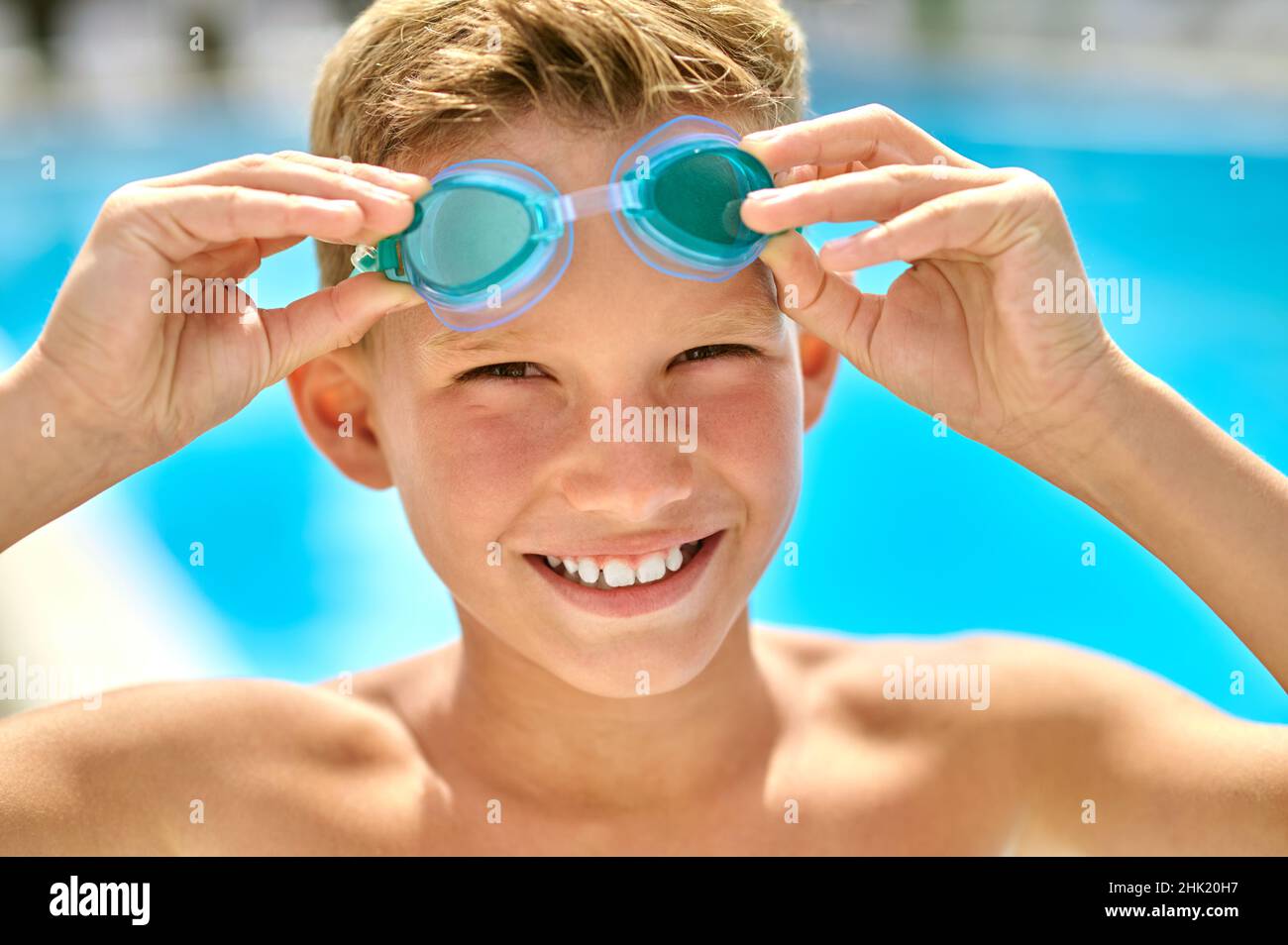 Gros plan sur le visage d'un garçon touchant des lunettes de natation Banque D'Images