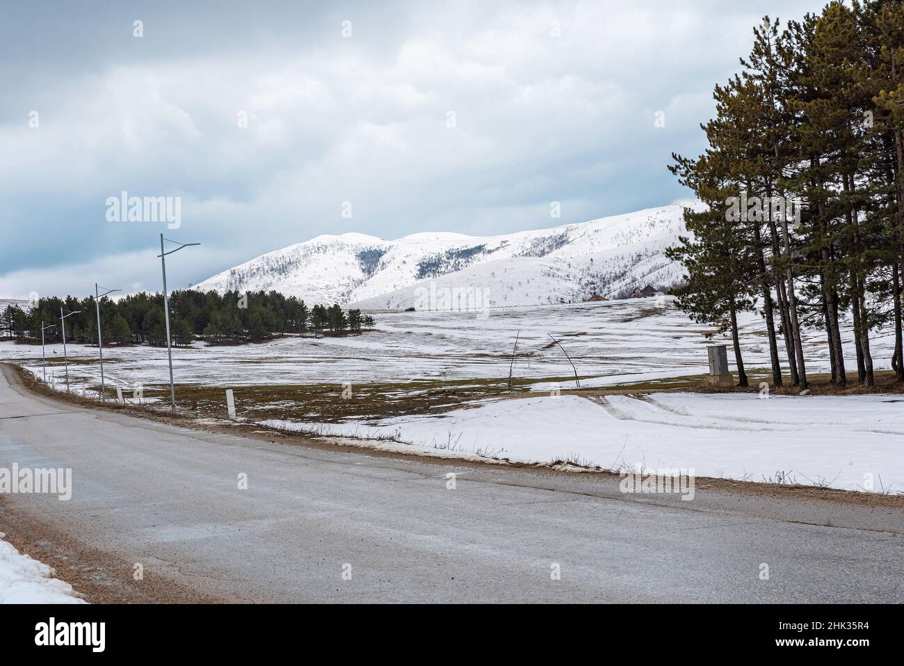 Vue latérale de la route asphaltée de montagne de campagne d'hiver avec neige et ciel nuageux Banque D'Images Vue latérale de la route asphaltée de montagne de campagne d'hiver avec neige et ciel nuageux Banque D'Images