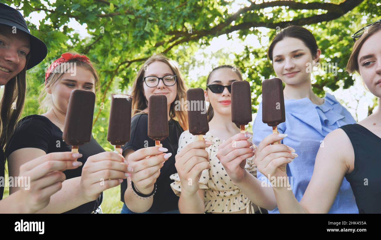Les amies tiennent la glace au chocolat sur un bâton de suite. Banque D'Images