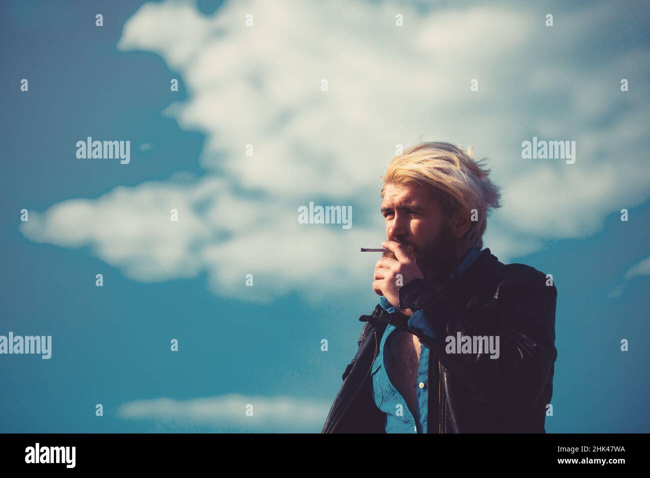 Cool homme méditerranéen avec la barbe fumer à l'extérieur dans l'environnement urbain Banque D'Images