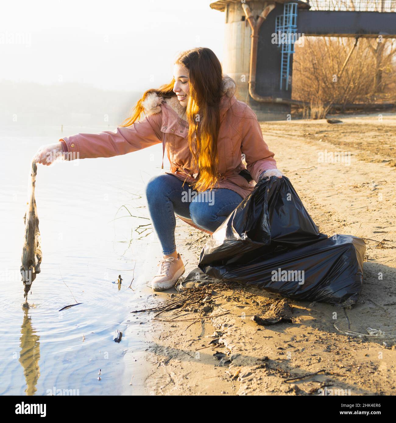 Une jeune femme nettoie l'eau des déchets plastiques Banque D'Images