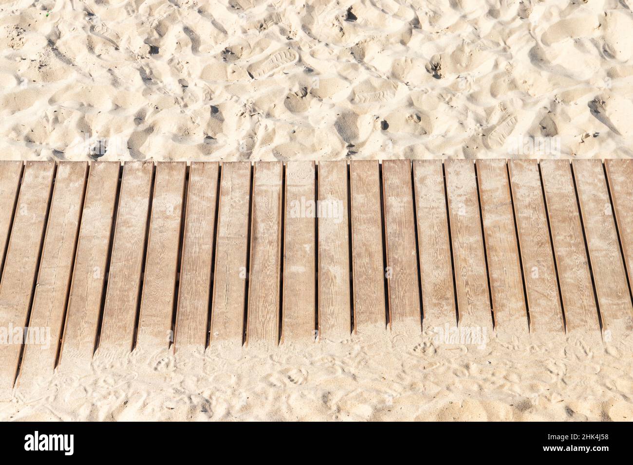 Une passerelle naturelle en bois non coloré traverse une plage de sable, texture d'arrière-plan Banque D'Images