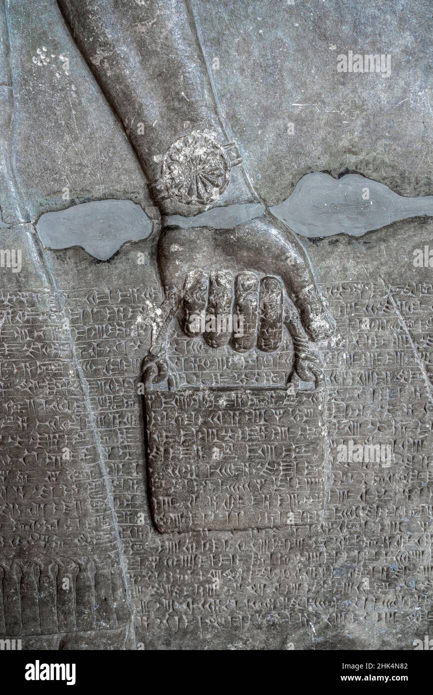 Relief antique représentant un seau d'eau sainte, porté par un génie ailé avec l'écriture cuneiform.Civilisation assyrienne et sumérienne (883-859 BCE). Banque D'Images