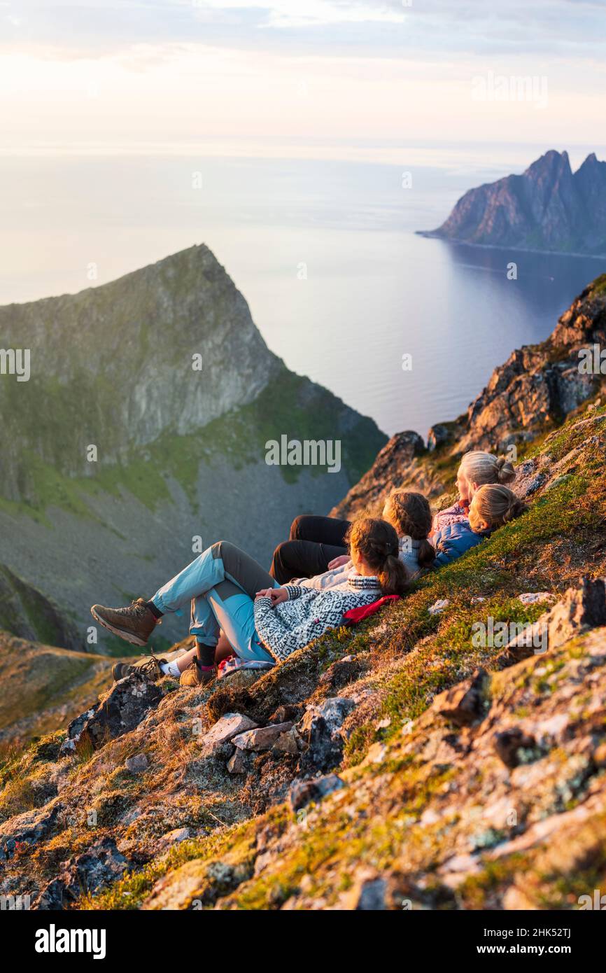 Jeunes femmes scandinaves profitant du coucher du soleil se détendant ensemble sur les rochers, île de Senja, comté de Troms, Norvège, Scandinavie,Europe Banque D'Images