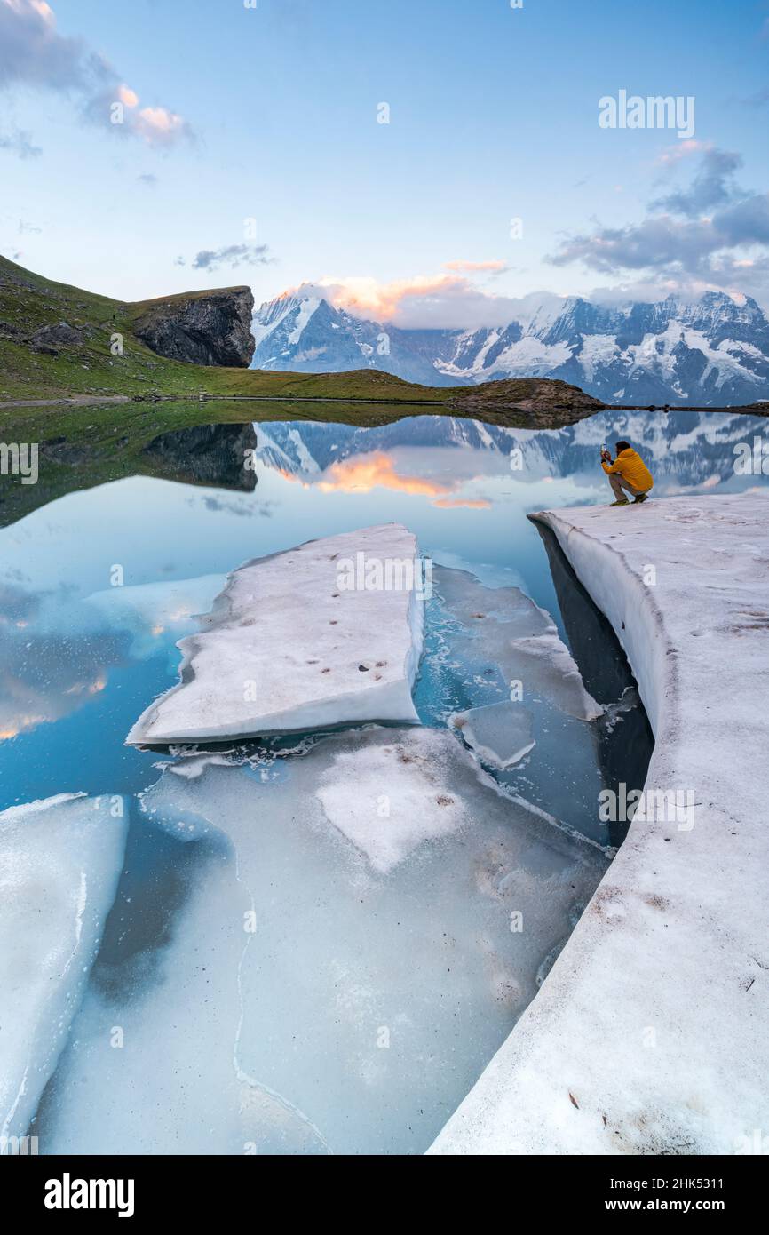 Homme photographiant la montagne Jungfrau depuis les rives gelées du lac Grauseeli au coucher du soleil, Murren Birg, canton de Berne, Suisse, Europe Banque D'Images