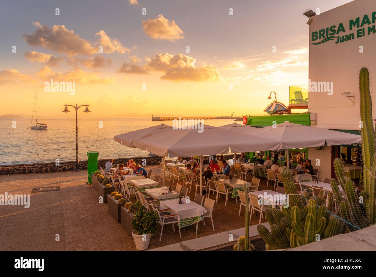 Vue sur le restaurant, le voilier sur la mer et Fuerteventura en arrière-plan au coucher du soleil, Playa Blanca, Lanzarote, îles Canaries, Espagne,Atlantique, Europe Banque D'Images
