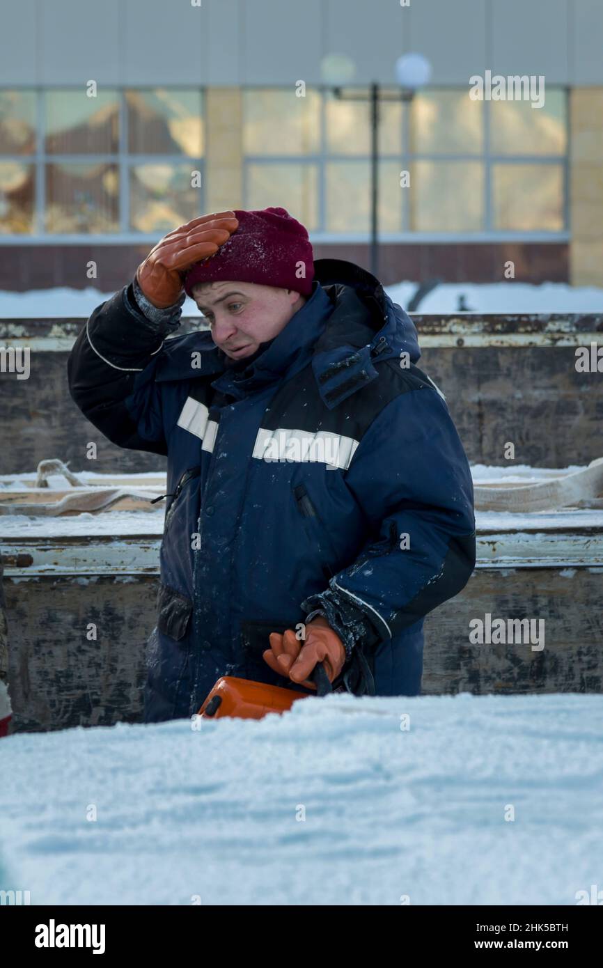 Portrait d'un assembleur de travail dans une veste bleue et un bonnet tricoté rouge sur le côté de la machine Banque D'Images