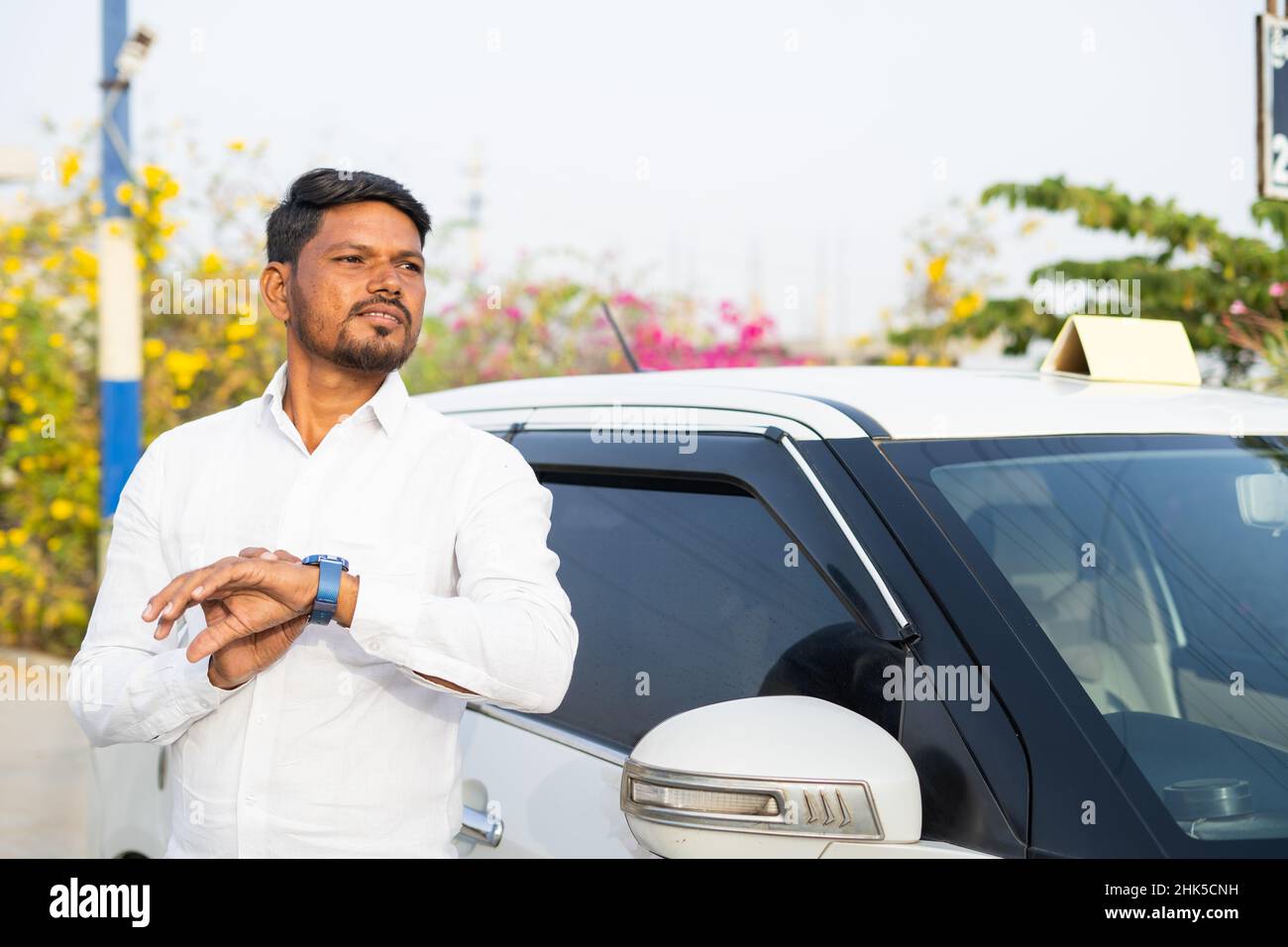 Inquiet chauffeur de taxi indien attendant le client devant la voiture - concept de service de réservation de taxi, style de vie de travail stressant et service de transport Banque D'Images