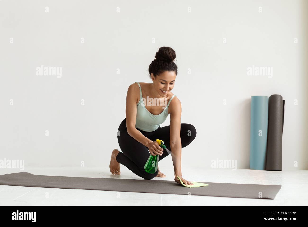 Jeune femme utilisant un spray désinfectant pour nettoyer le tapis de yoga  avant la formation Photo Stock - Alamy