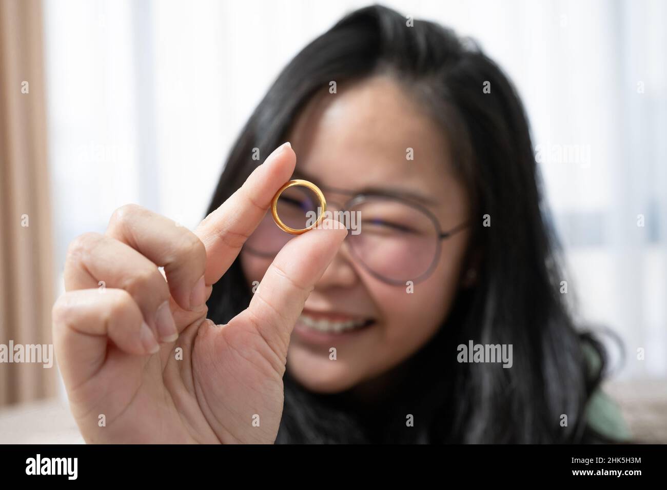 Gros plan sur de magnifiques verres la femme asiatique joue l'anneau doré dans sa chambre Banque D'Images