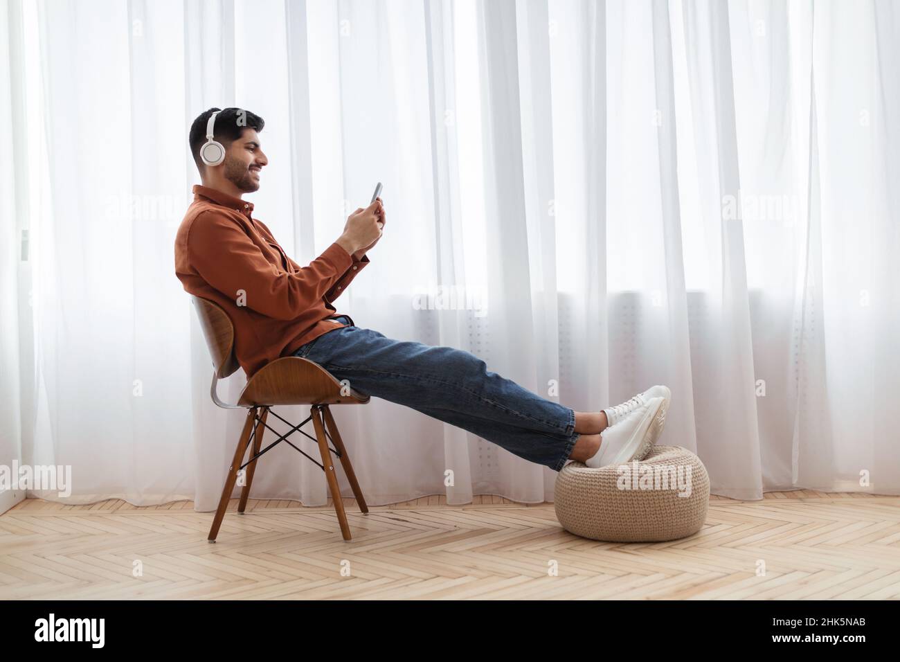 Un homme arabe heureux utilisant un téléphone portable avec un casque Banque D'Images