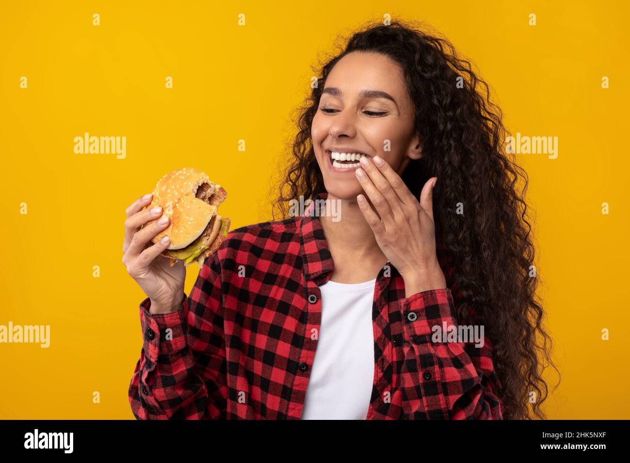 Happy Raughing Lady Eating Burger au Studio Banque D'Images