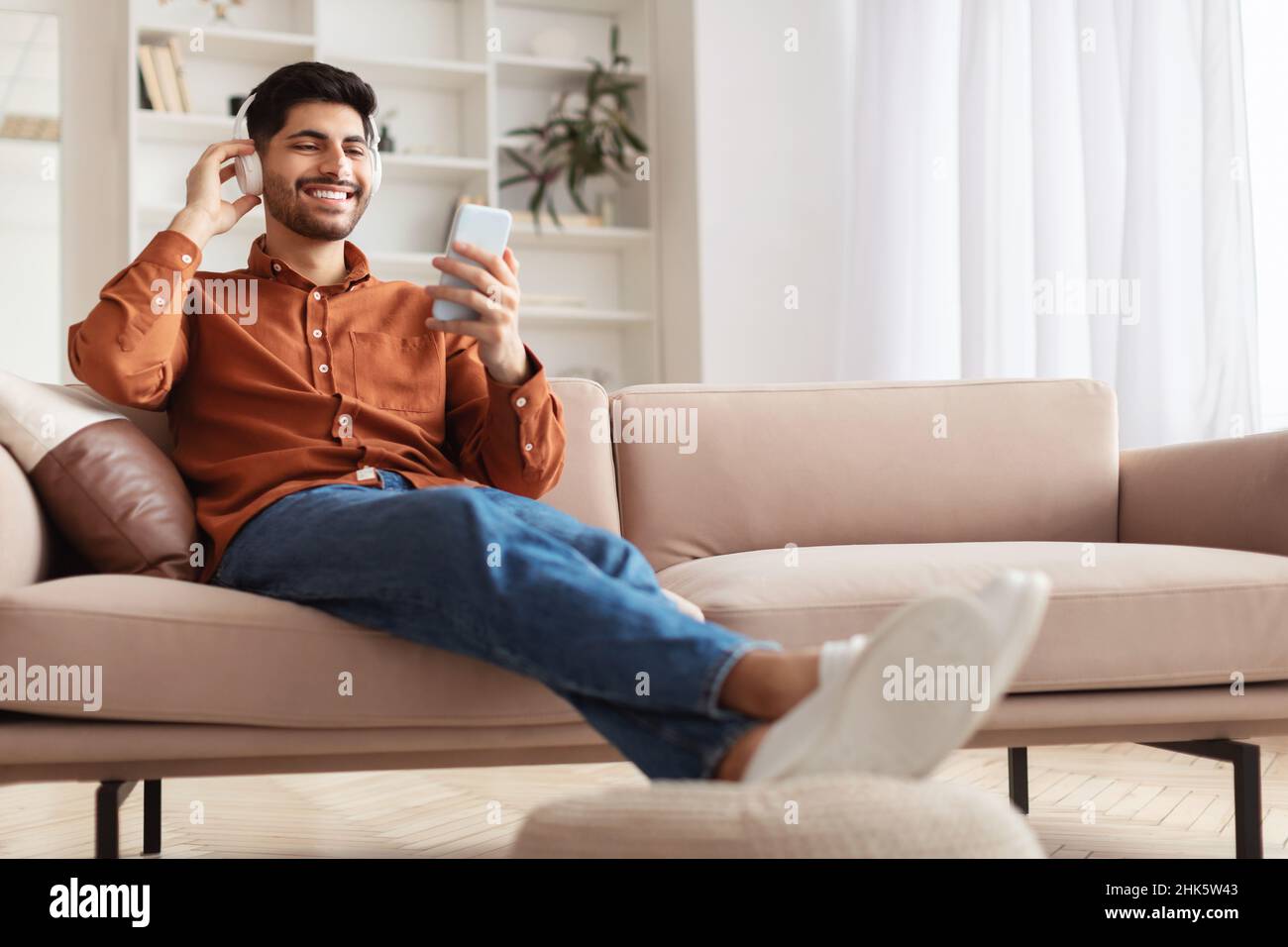 Un homme arabe heureux utilisant un téléphone portable avec un casque Banque D'Images