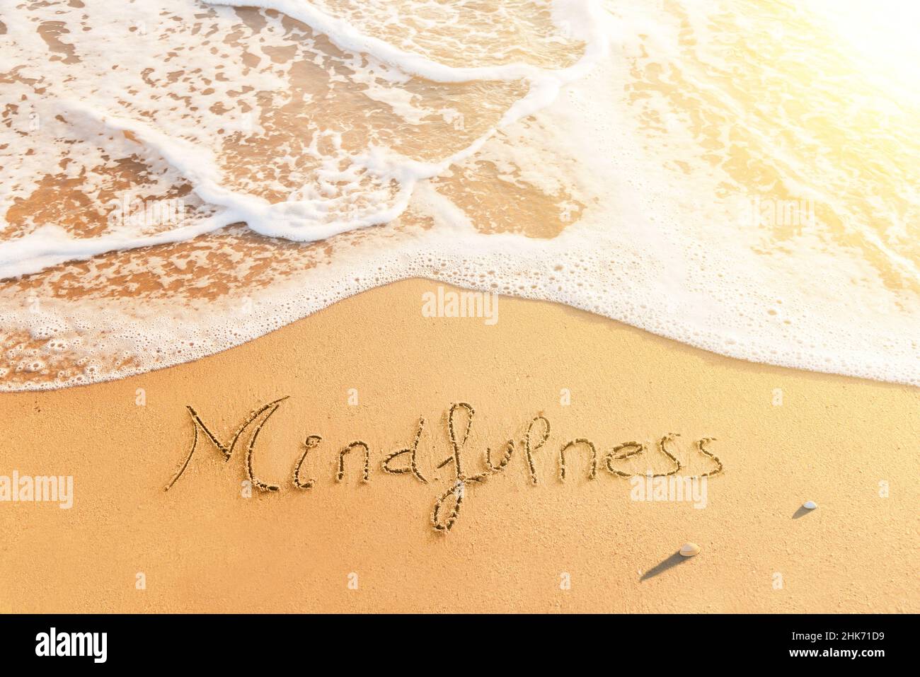 Mot 'plénitude' écrit sur le sable de la plage.Message positif écrit sur le bord de mer au coucher du soleil Banque D'Images