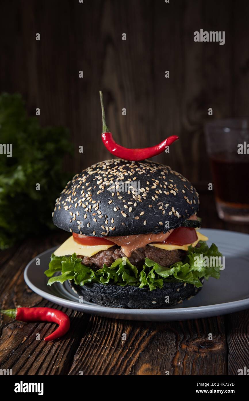 Hamburger de bœuf au piment et au pain noir sur fond de bois rustique. Banque D'Images