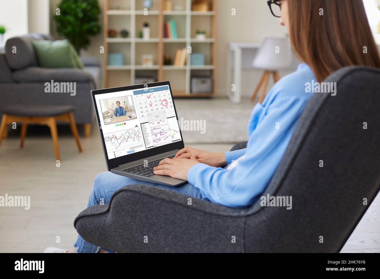 Femme assise à la maison, travaillant sur un ordinateur portable, utilisant le calendrier et ayant des appels vidéo Banque D'Images