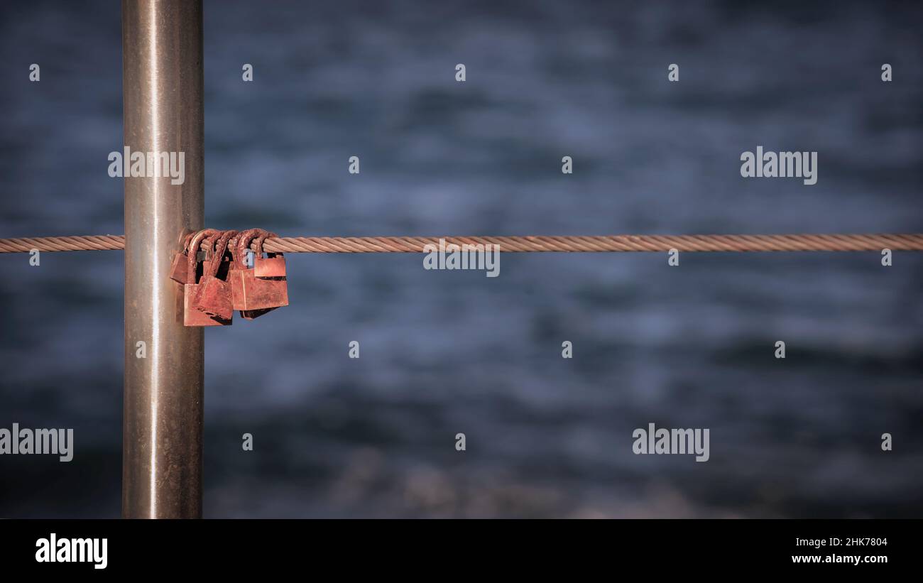 Cadenas suspendus au câble métallique Rusty contre la mer Banque D'Images