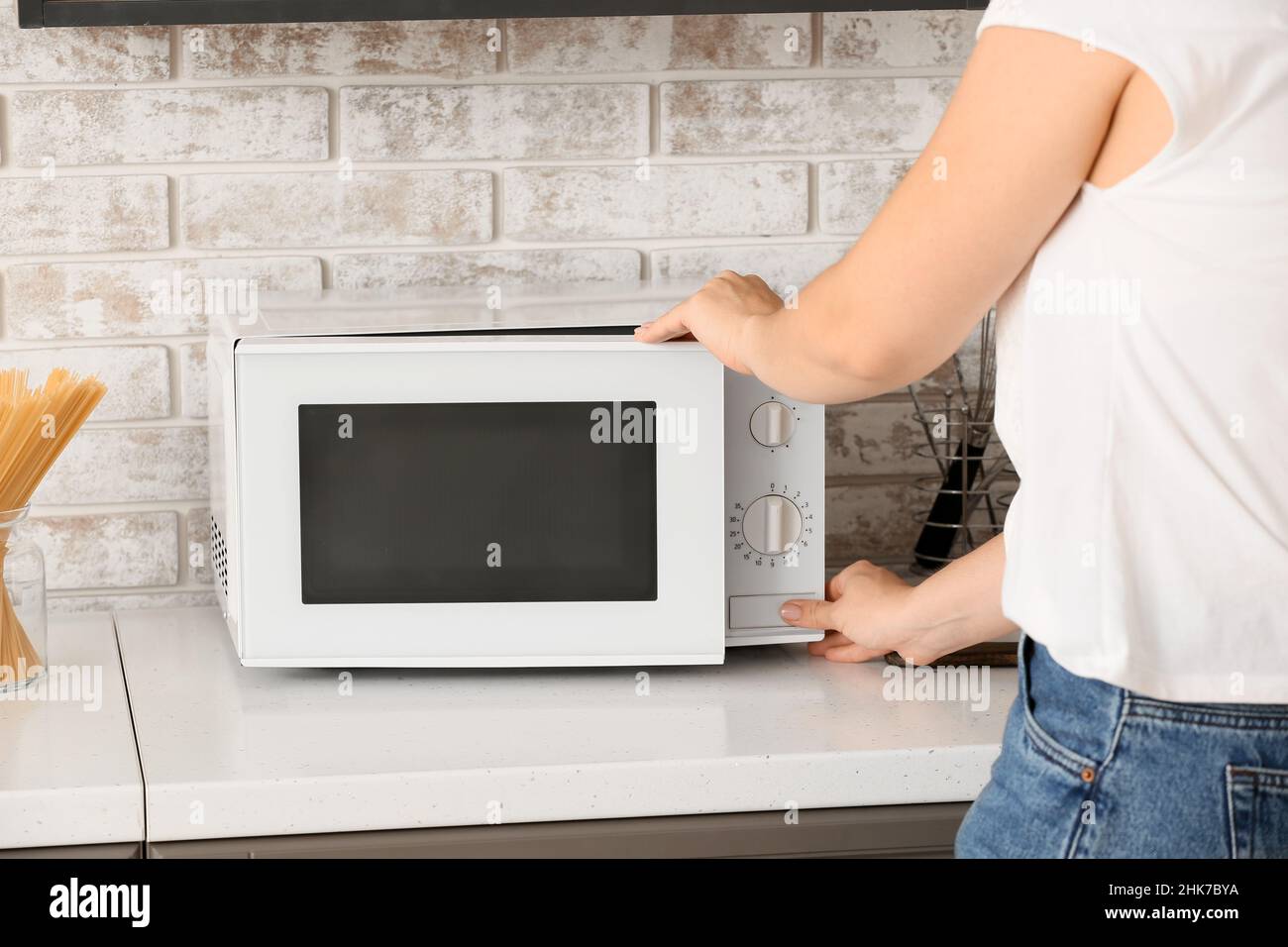 Femme utilisant un four à micro-ondes dans la cuisine Banque D'Images