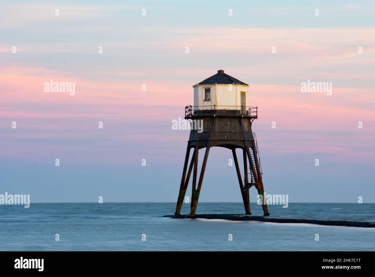 De belles nuances de rouge et de rose causées par le coucher du soleil illuminent les nuages derrière le phare de Dovercourt.Harwich et Dovercourt Beach, Essex Nord, Royaume-Uni Banque D'Images