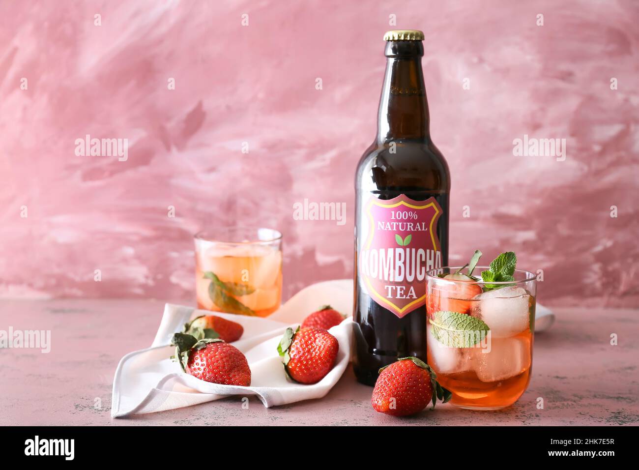 Bouteille et verre de kombucha frais de fraise glacé sur fond rose Banque D'Images