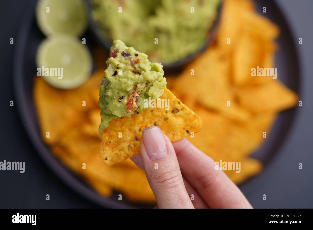 Gros plan de la main de femme tenant le guacamole et les jetons ou les nachos.Vue de dessus Banque D'Images