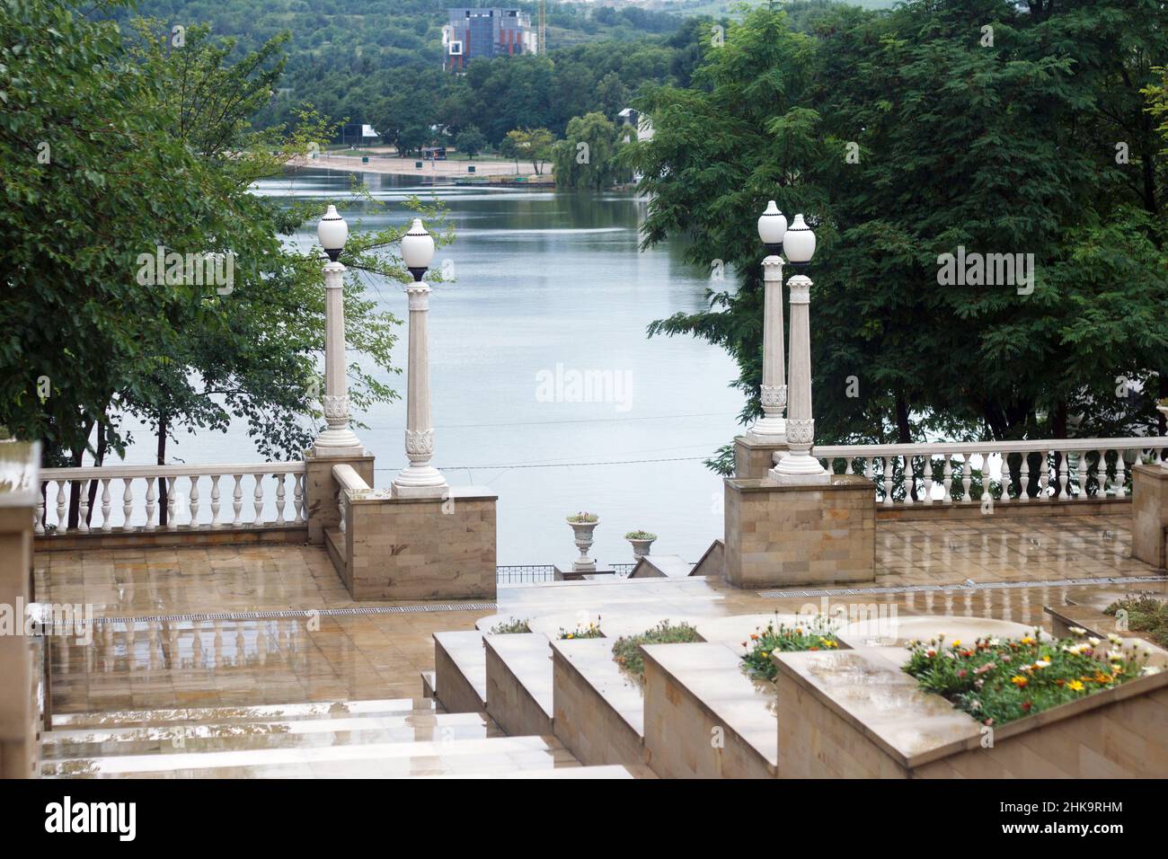 Panorama du parc moderne avec de belles colonnes blanches en béton, des lampes et une vue sur le lac par temps pluvieux Banque D'Images