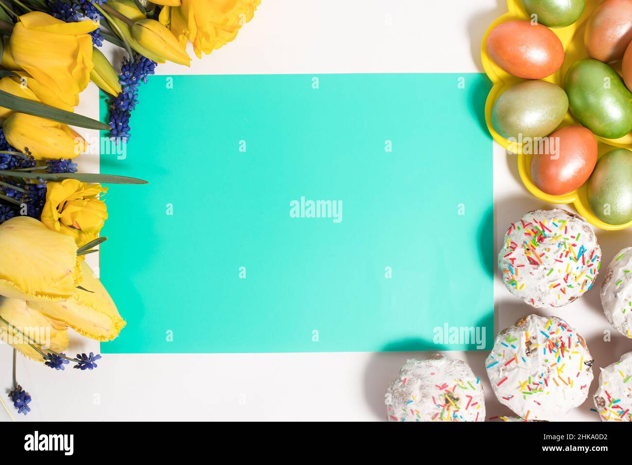 Disposition de Pâques avec tulipes, gâteaux et oeufs sous forme de cadre avec un endroit pour le texte au centre, vue de dessus. Banque D'Images