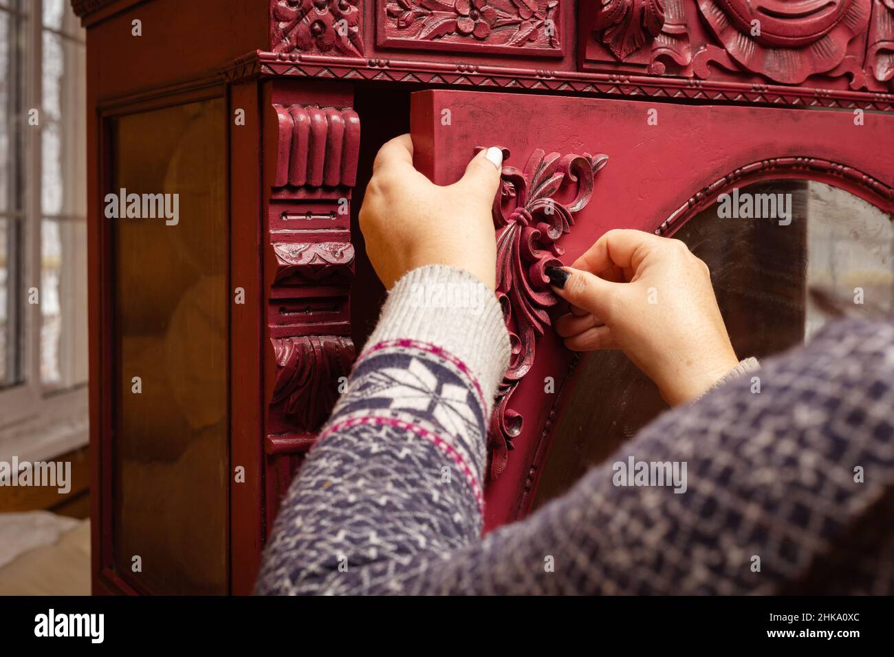 Gros plan des mains de femme d'âge moyen encollage de nouvelles belles décorations en bois sculptées au carton rouge dans l'atelier pour la restauration de meubles.Écologique.Réutiliser Banque D'Images