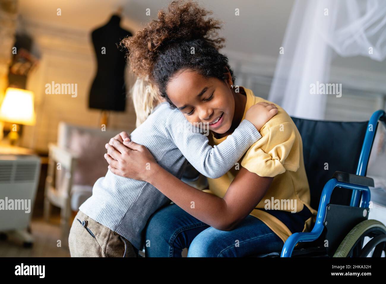 Bonne famille multiethnique. Petite fille souriante avec handicap en fauteuil roulant à la maison Banque D'Images