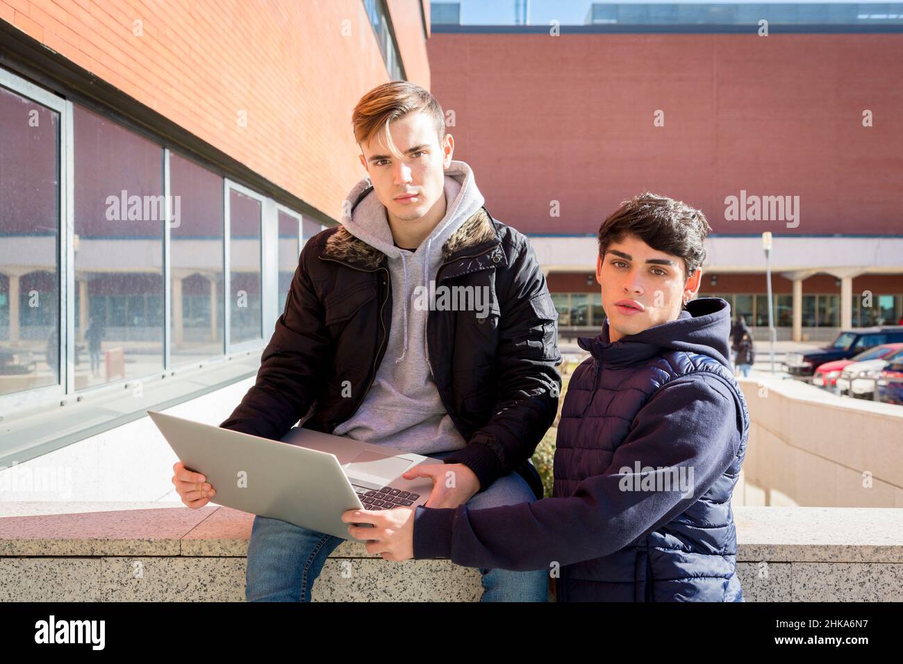 deux étudiants, un assis et un debout avec un ordinateur portable regardant la caméra Banque D'Images