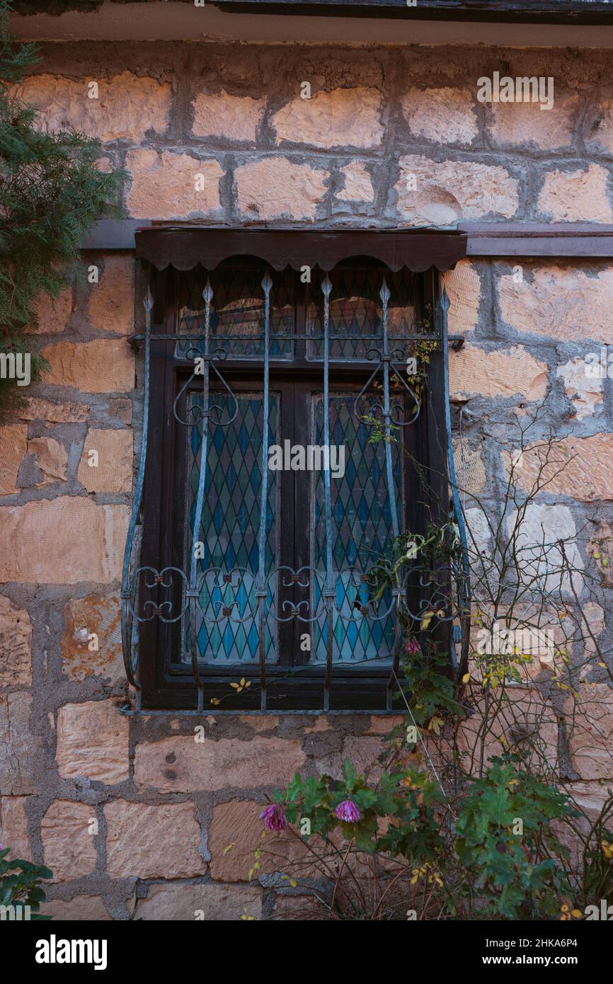 Fenêtre de maison en pierre vintage avec clôture de fer forge. Banque D'Images